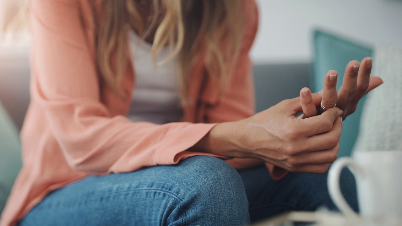 Eine Frau sitzt auf dem Sofa und dreht nervös an ihrem Ring | Nervosität und innere Unruhe bekämpfen