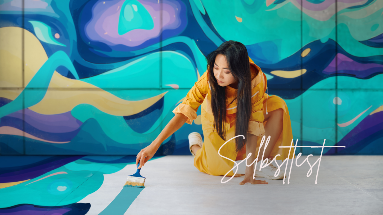 Eine Frau in gelbem Overall bemalt eine bunte Wand.