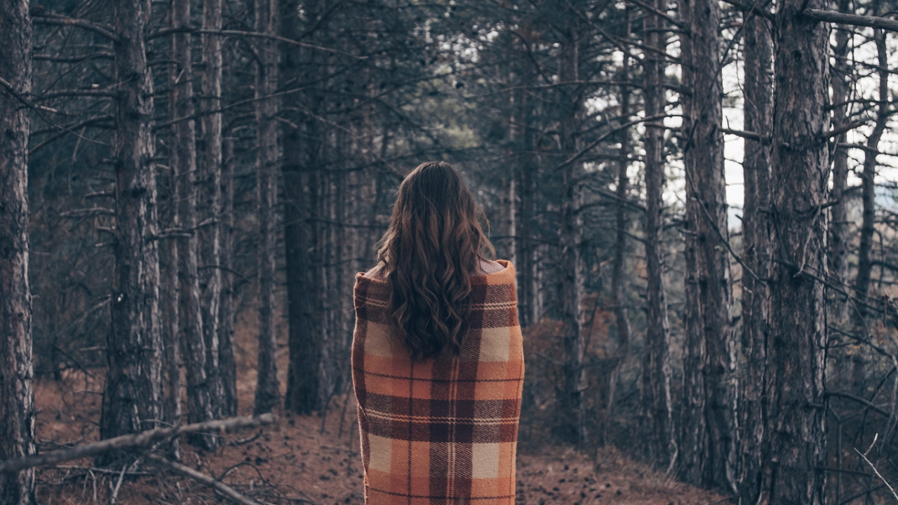Mabon: Das zweite Erntefest im Jahreskreis feiern Frau steht mit Rücken zu Betrachter vor einer Waldlandschaft