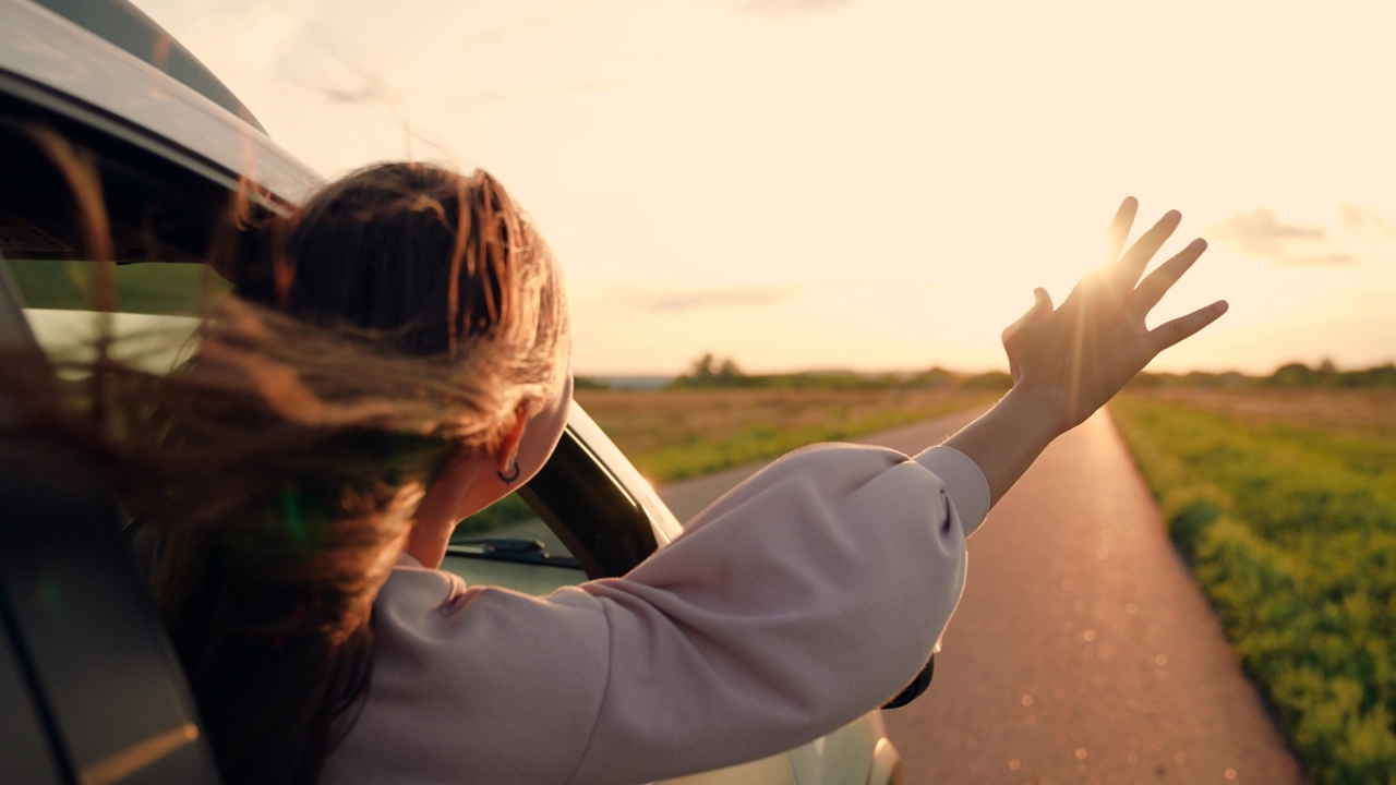 Frau in Auto mit ausgestrecktem Arm