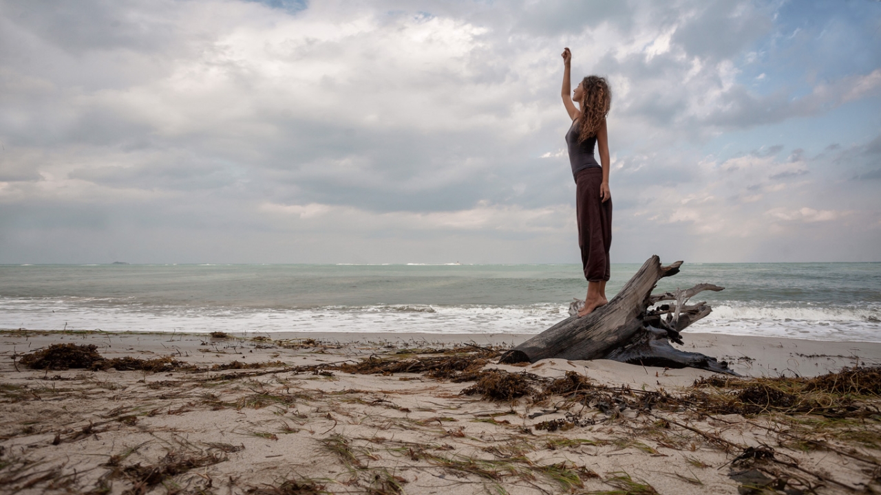 Frau am Strand mit zum Himmel gestreckter Hand