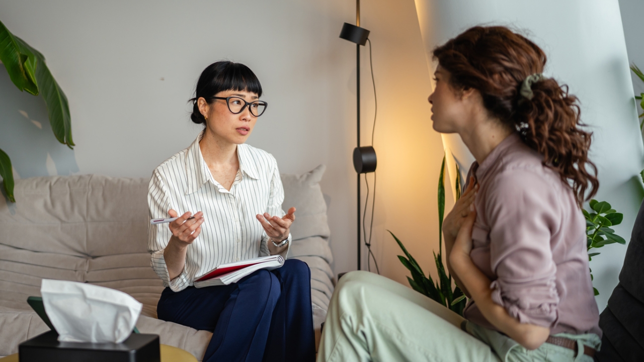 Zwei Frauen die gegenüber einander sitzen und sich unterhalten und gestikulieren
