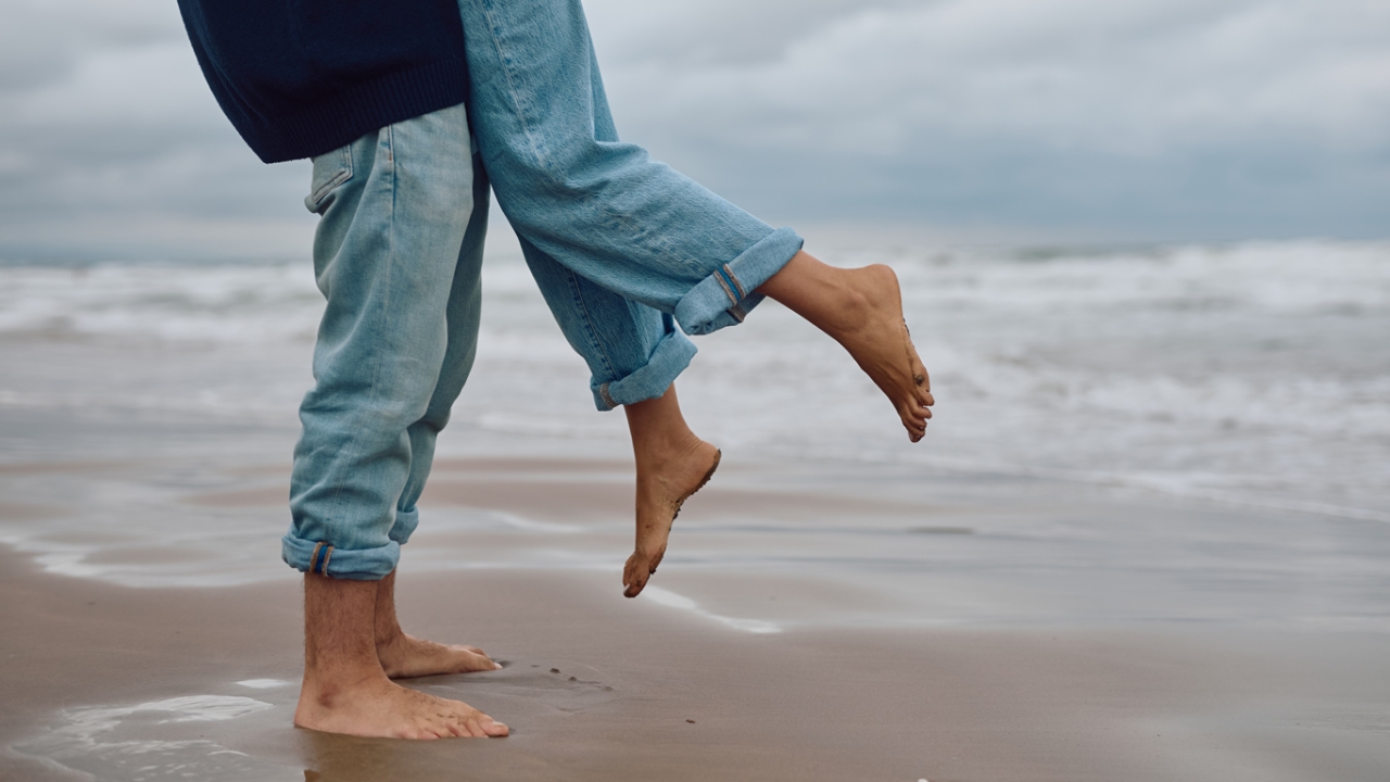 Liebe im Buddhismus: Eine Person hebt im Sand eine andere Person im Sprung hoch.
