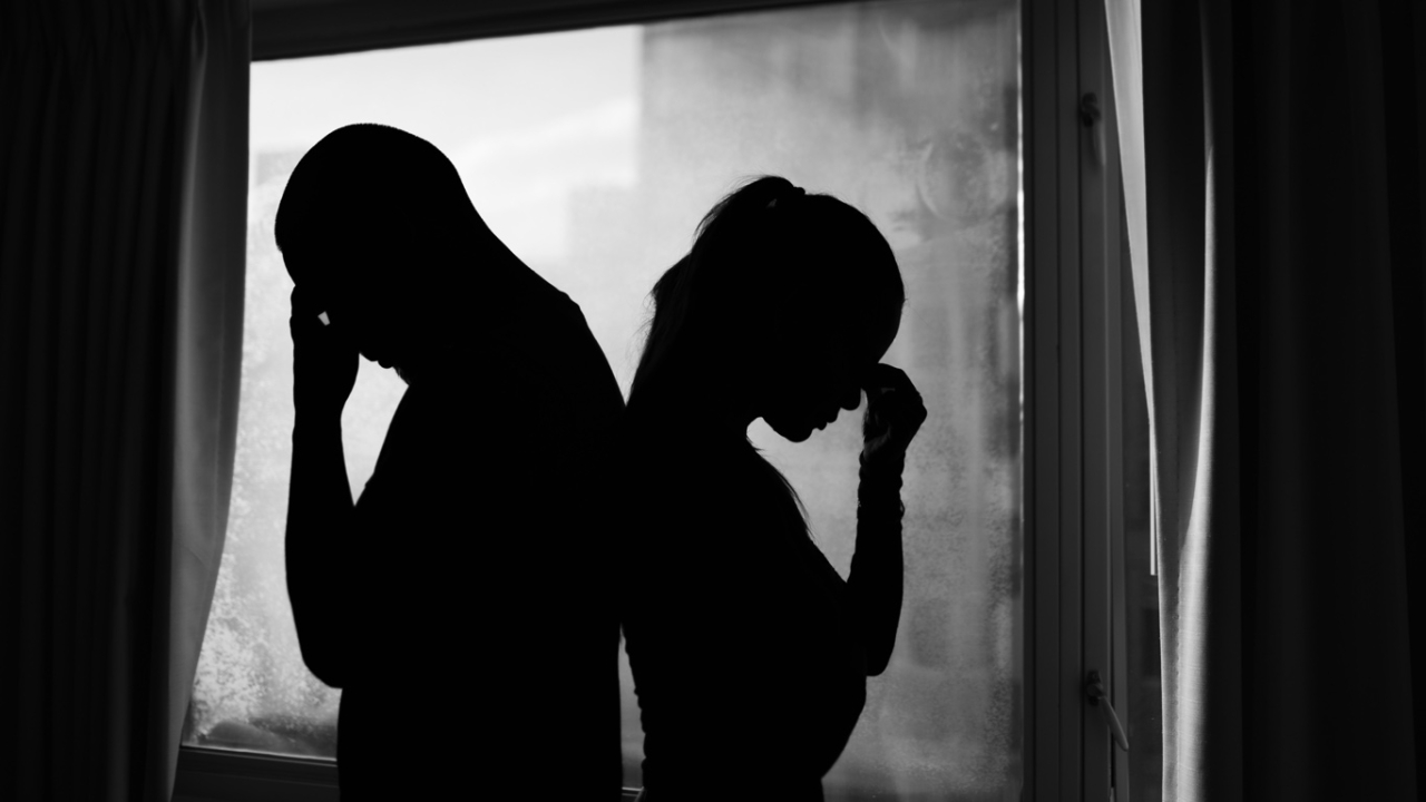 Mann und Frau die Rücken an Rücken stehen mit dem Gesicht auf der Hand abgestützt
